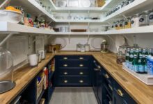Small butler pantry with open shelves, wood counters, dark lower cabinets, and neatly arranged jars