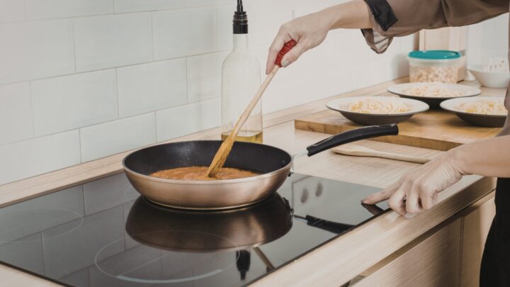 Person stirs food on an induction cooktop in a modern kitchen