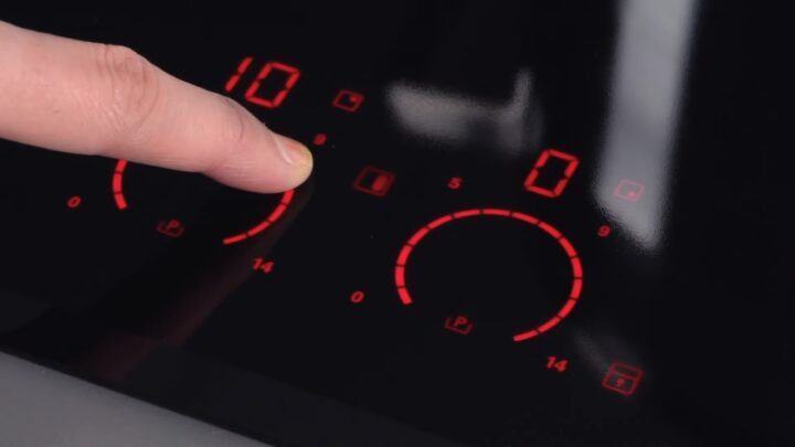 Finger adjusts the touch controls on an induction cooktop
