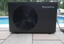 Black pool heat pump installed beside a backyard pool