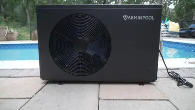 Black pool heat pump installed beside a backyard pool