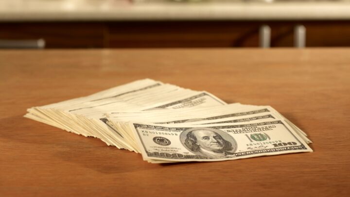 Stack of cash on a kitchen counter for cooktop cost comparison
