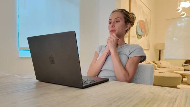 Alix Earle sits at a table with a laptop in a bright room