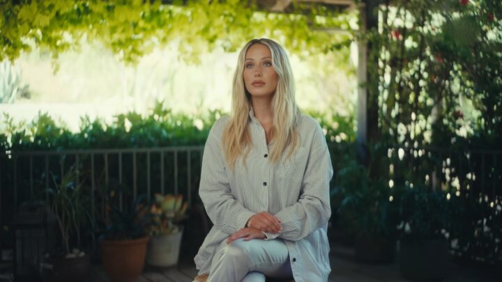 Alix Earle sits on a garden patio in a striped shirt