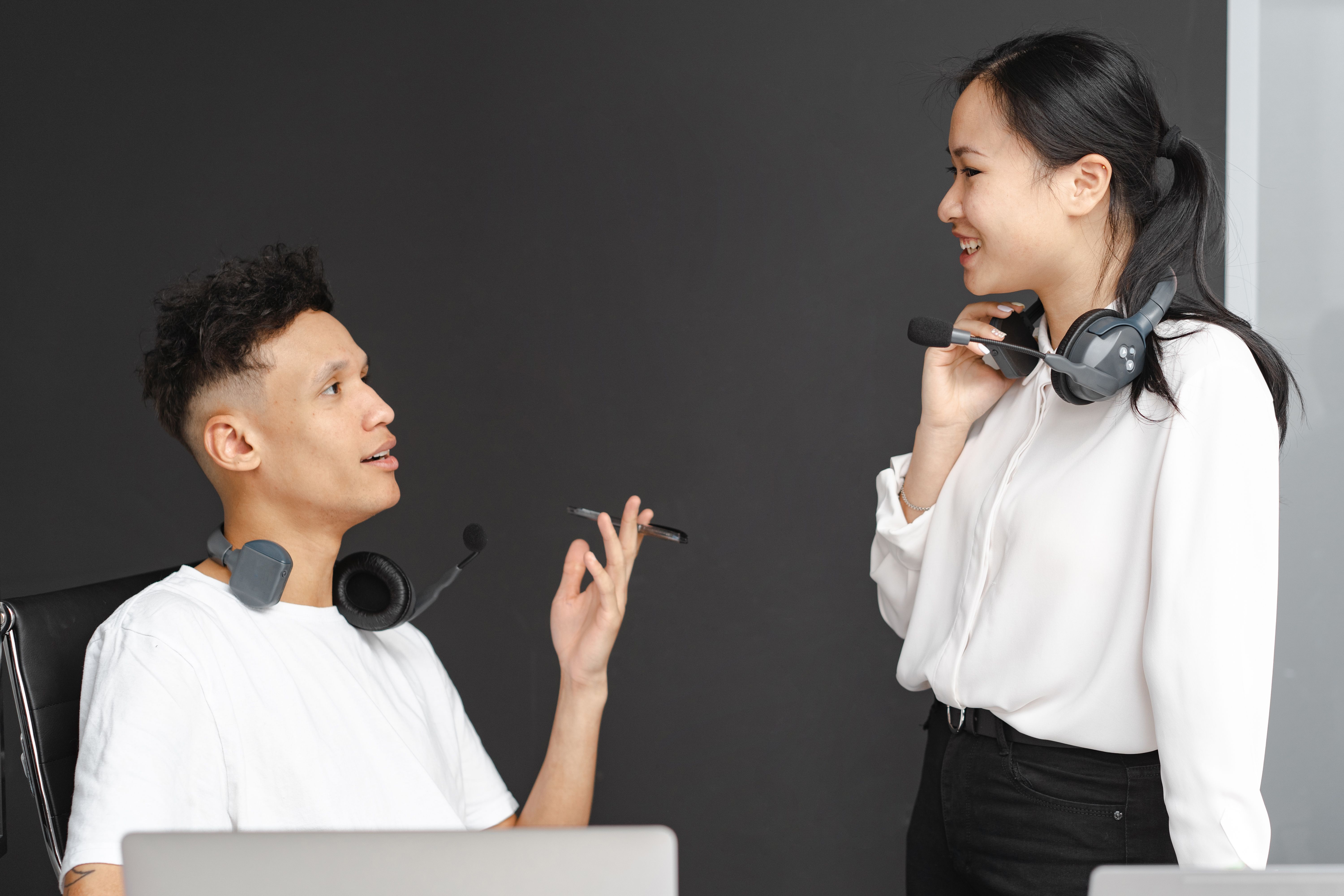 Two colleagues with headsets chatting in a modern office, representing business communication teams