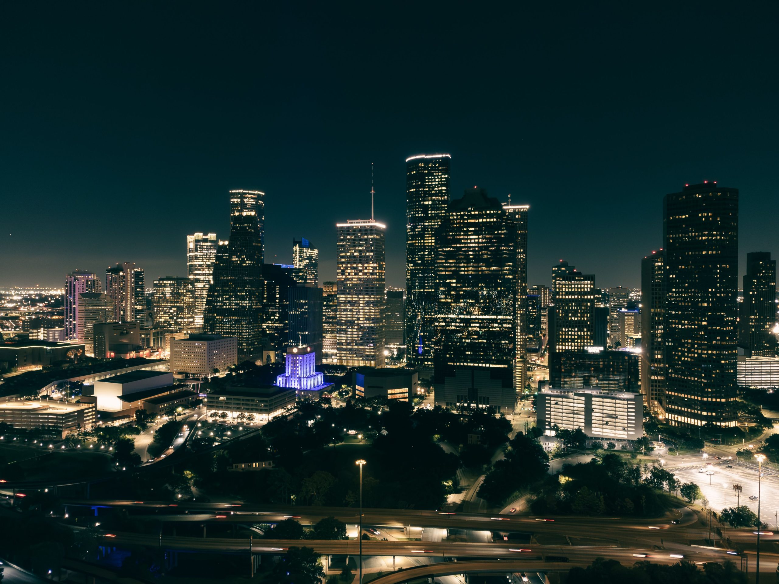 Aerial view of a vibrant city skyline at night with illuminated skyscrapers and glowing roads