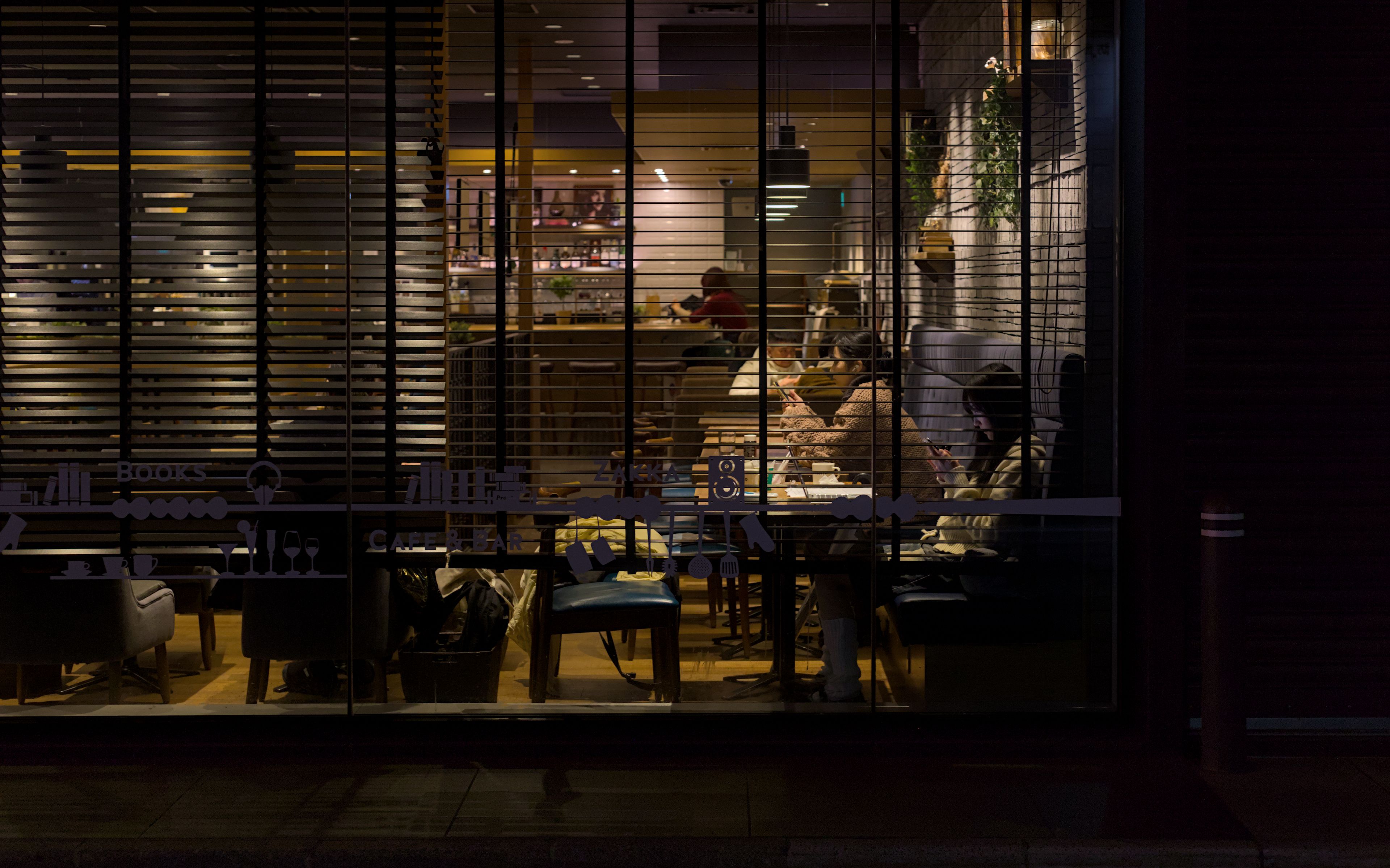 Cozy Kyoto cafe illuminated with soft lighting at night, capturing a warm late-night urban atmosphere