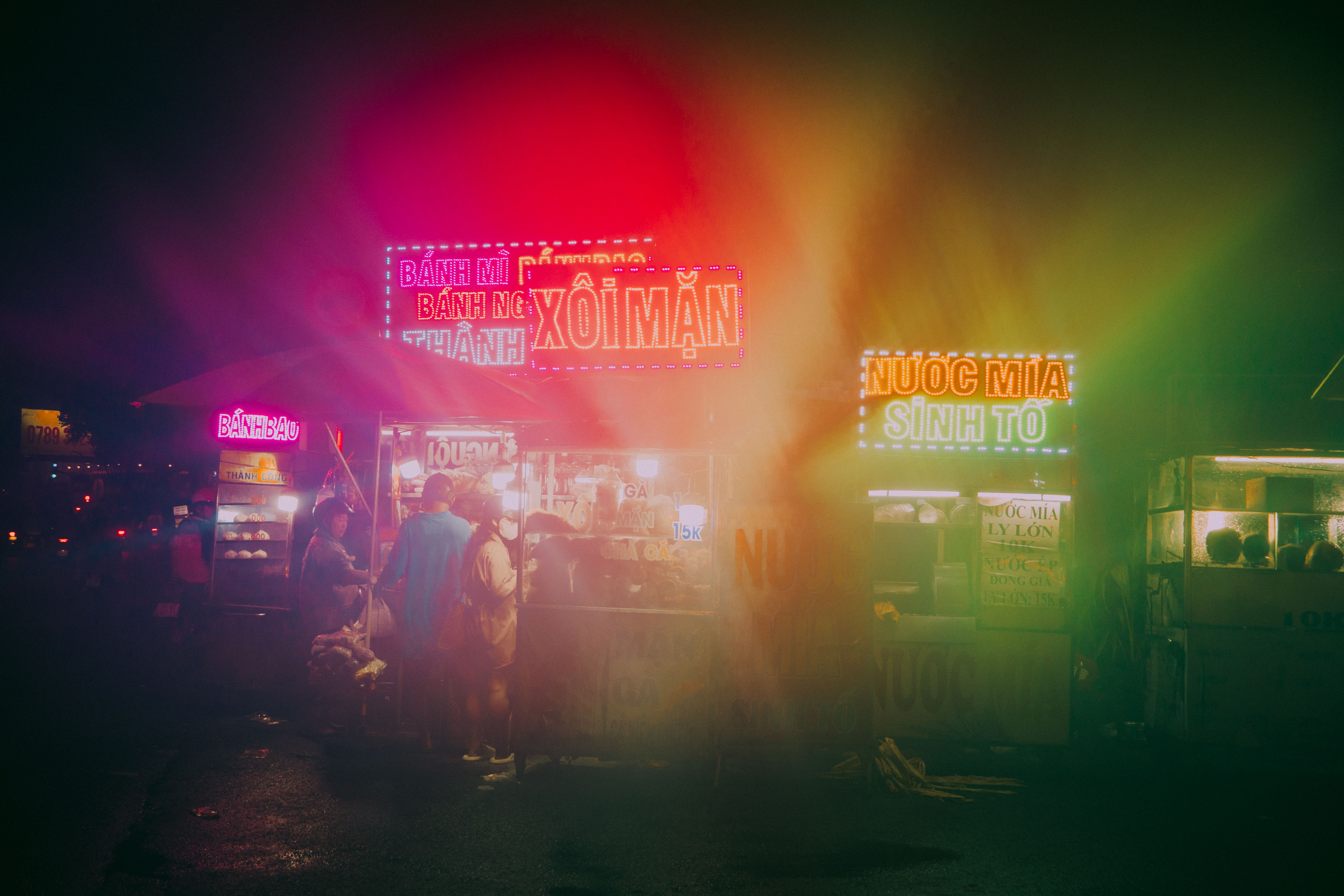 Neon-lit street food stalls creating a vibrant atmosphere at a bustling local night market